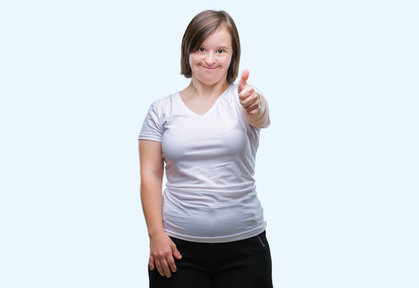 Молодая взрослая женщина с синдромом Дауна на изолированном фоне делает счастливый жест вверх рукой. Утверждение выражения лица, смотрящего в камеру с успехом
. - Фото, изображение