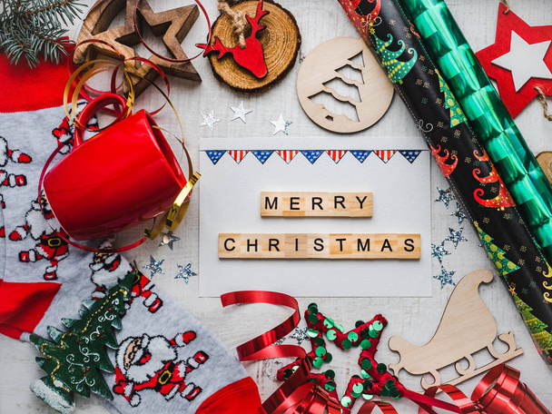 Christmas card. Colorful Christmas decorations and toys, drawing of USA Flag, warm socks with Santa Claus, red mug and ribbon on a white, wooden surface. Merry Christmas. Top view, close-up, flat lay - 写真・画像