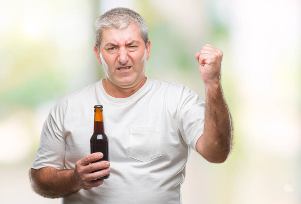 Όμορφος ανώτερος άνθρωπος πίνοντας μπύρα μπουκάλι πάνω από το απομονωμένο φόντο ενοχλημένοι και απογοητευμένοι φωνάζει με θυμό, τρελό και φωνάζει με σήκωσε το χέρι, ο θυμός έννοια - Φωτογραφία, εικόνα