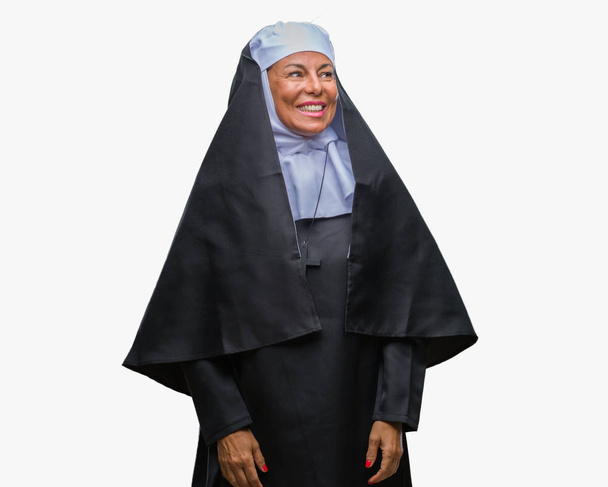 Monja católica cristiana mayor de mediana edad sobre un fondo aislado mirando hacia otro lado con sonrisa en la cara, expresión natural. Riendo confiado
. - Foto, Imagen
