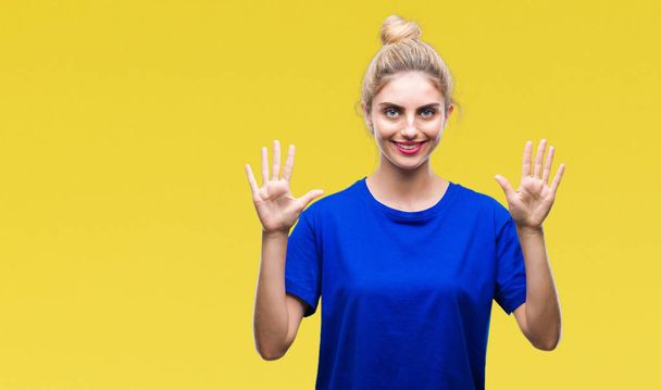 Молода красива блондинка і блакитні очі жінка в синій футболці над ізольованим тлом, показуючи і вказуючи пальцями номер десять, посміхаючись впевнено і щасливо
. - Фото, зображення