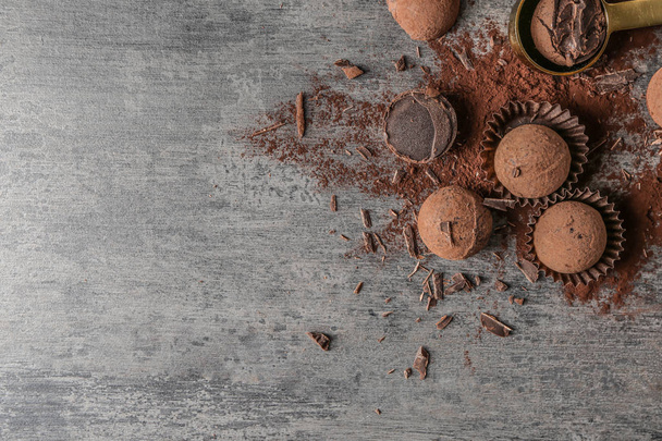 Вкусные шоколадные трюфели с какао-порошком на сером столе
 - Фото, изображение