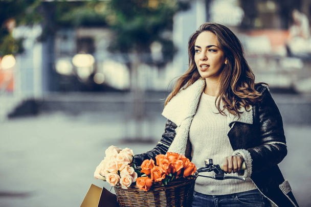 Hermosa joven sonriente mujer con su bicicleta y bolsas de compras en la ciudad. Belleza, moda y estilo de vida
. - Foto, imagen