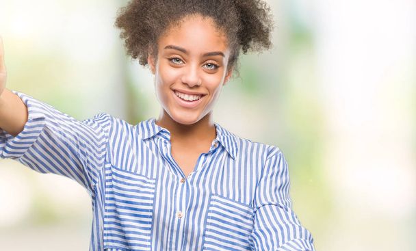 Young afro american woman over isolated background looking at the camera smiling with open arms for hug. Cheerful expression embracing happiness. - Photo, image