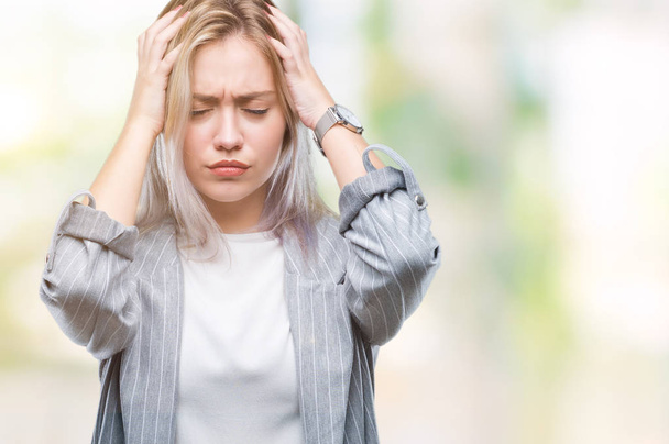 Молодая блондинка бизнес-женщина в куртке на изолированном фоне страдает от головной боли отчаянно и стресс, потому что боль и мигрень. Руки на голову
. - Фото, изображение