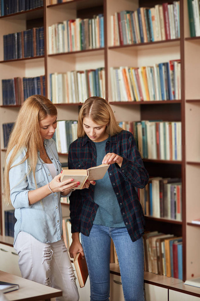 Two young female students shooses books at the library - Foto, immagini