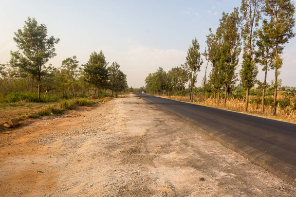 Недавно построенная дорога, пересекающая сельскую местность Саванны, делает возможным транспортировку
. - Фото, изображение