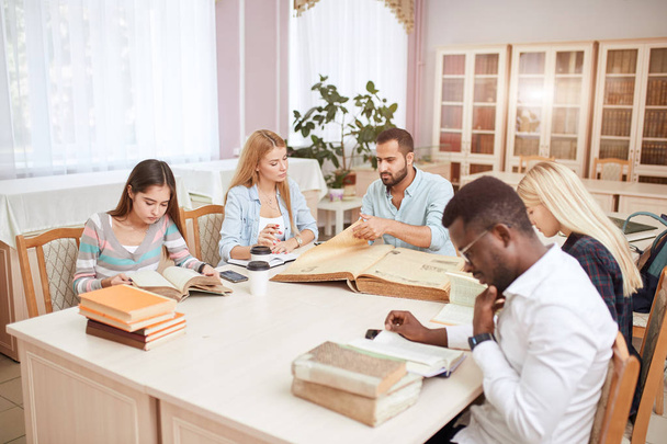 Group of multiracial people studying with books in college library. - Photo, image