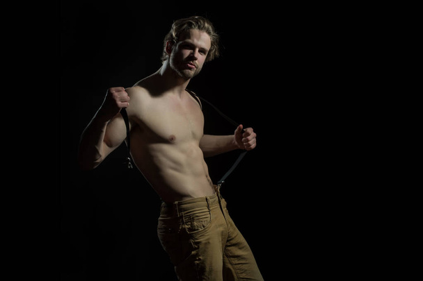 Sexy man played with his suspenders for trousers on a black background. Seductive fashionable and sensual man - Photo, image