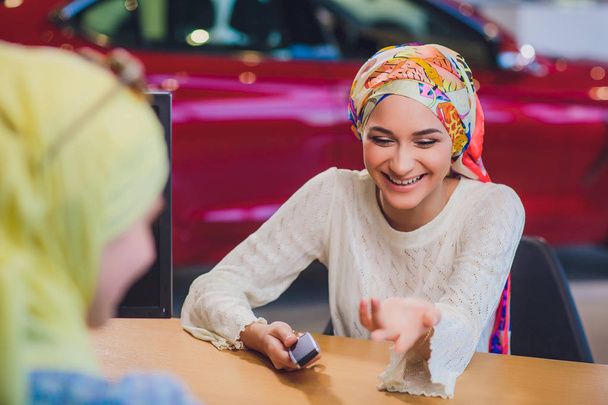 Beautiful woman enjoying happy moment getting car key from car seller auto salon. muslim woman in hijab - Фото, зображення