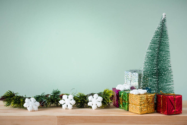 Christmas background. A small Christmas tree and boxes with gifts on a wooden table. Green background. Space for text. New Year's background. - Photo, Image