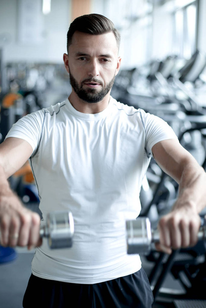 close up.stylish young man working with dumbbells in the gym. - Fotografie, Obrázek