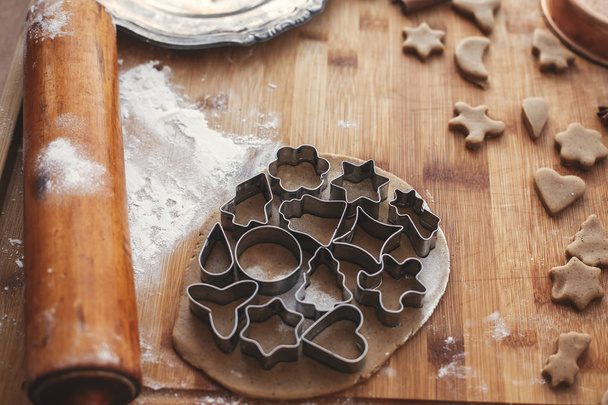 Gingerbread dough with metal cutters for christmas cookies on rustic table with wooden rolling pin, cinnamon ,anise, cones, christmas decorations. Atmospheric stylish image - Foto, immagini