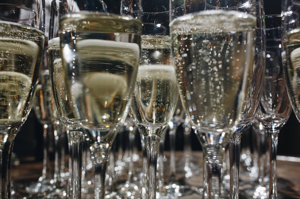 Sommelier giet uit een fles champagne in een glas aan de tafel in het restaurant. - Foto, afbeelding