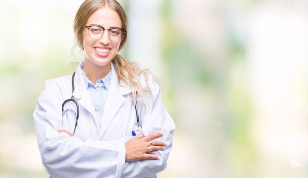 Bella giovane donna medico bionda indossa uniforme medica su sfondo isolato volto felice sorridente con le braccia incrociate guardando la fotocamera. Persona positiva
. - Foto, immagini