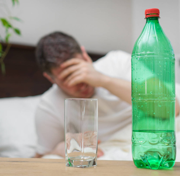 Man drinking mineral water and suffering from hangover. - Photo, Image