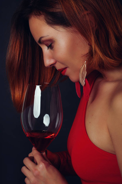 Portrait of a beautiful young woman in profile with a glass of red wine. Author retouching. - Foto, Imagen
