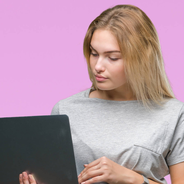 junge kaukasische Frau mit Computer-Laptop über isoliertem Hintergrund mit einem selbstbewussten Gesichtsausdruck auf intelligentem Gesichtsdenken ernst - Foto, Bild