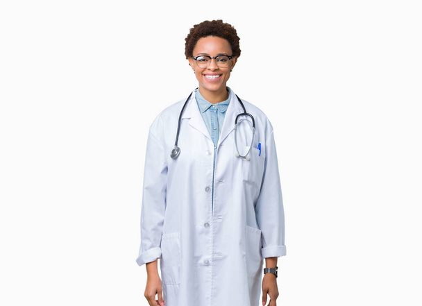 Yüzünde mutlu ve güzel bir gülümseme ile izole arka plan üzerinde tıbbi ceket giyen genç Afro-Amerikan doktor kadın. Şanslı kişi. - Fotoğraf, Görsel