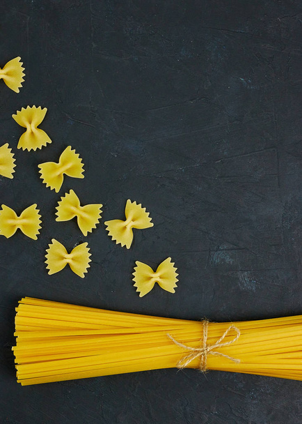 Uncooked pasta tied with a rope on concrete against black background. copy space. view from above. - 写真・画像