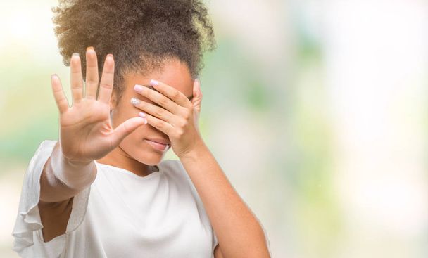 Young afro american woman over isolated background covering eyes with hands and doing stop gesture with sad and fear expression. Embarrassed and negative concept. - Photo, image