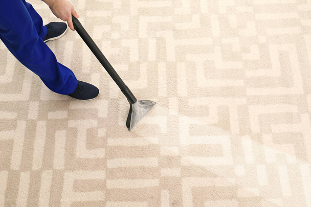 Man removing dirt from carpet with professional vacuum cleaner in room, top view - Fotoğraf, Görsel