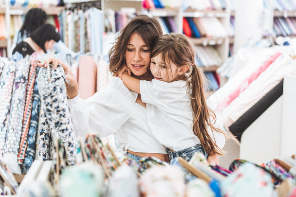 Mom and daughter in the fabric store choose fabric - Foto, Imagen