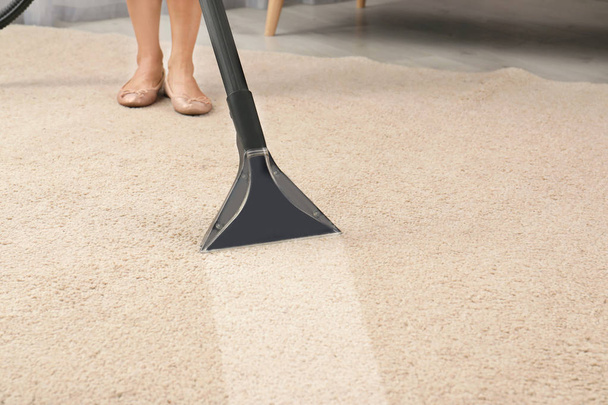 Woman removing dirt from carpet with vacuum cleaner in room - Foto, Bild