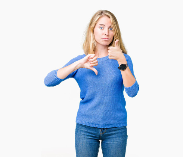 Beautiful young woman wearing blue sweater over isolated background Doing thumbs up and down, disagreement and agreement expression. Crazy conflict - Zdjęcie, obraz