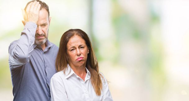 Middle age hispanic business couple over isolated background suffering from headache desperate and stressed because pain and migraine. Hands on head. - Фото, изображение