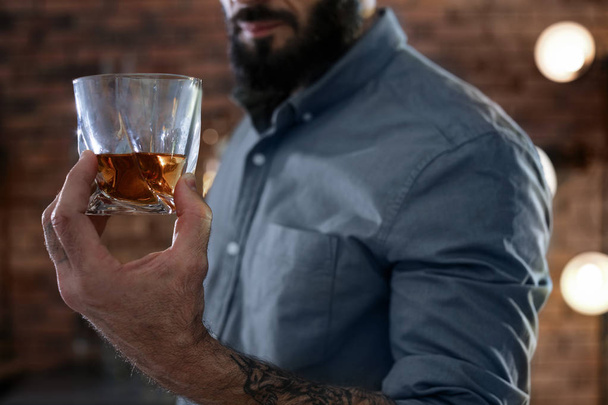 Man with glass of whiskey indoors, closeup - Foto, imagen