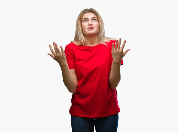 Young caucasian woman over isolated background crazy and mad shouting and yelling with aggressive expression and arms raised. Frustration concept. - Фото, изображение