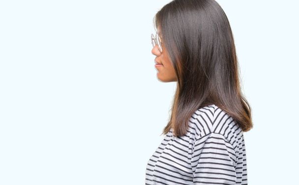 Genç Asyalı kadın gözlük izole arka tarafına, seyir üzerinde dinlenmek doğal yüz emin gülümseme ile pozuyla profili. - Fotoğraf, Görsel