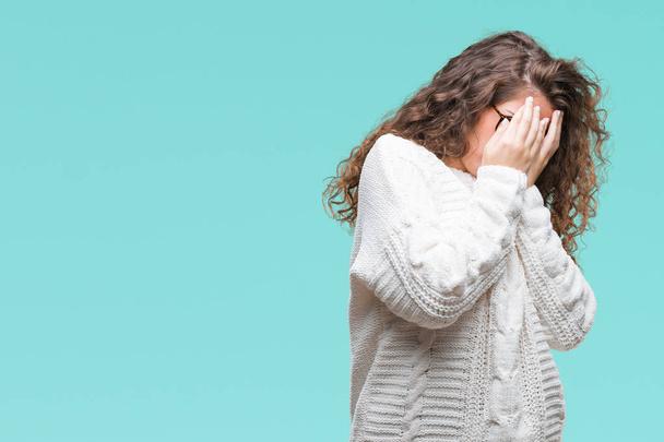 Beautiful brunette curly hair young girl wearing winter sweater over isolated background with sad expression covering face with hands while crying. Depression concept. - Photo, Image