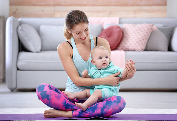 Young sportive woman doing exercise with her son at home. Fitness training - Foto, imagen