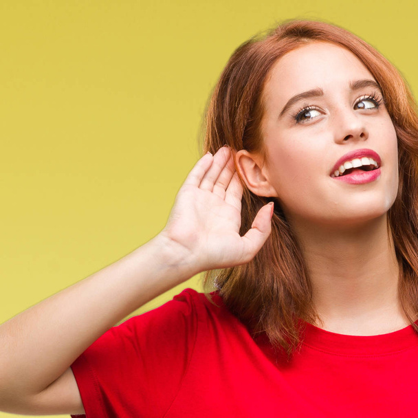Young beautiful woman over isolated background smiling with hand over ear listening an hearing to rumor or gossip. Deafness concept. - Foto, Imagen