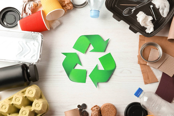 Recycling symbol and different garbage on wooden background, top view - Фото, зображення