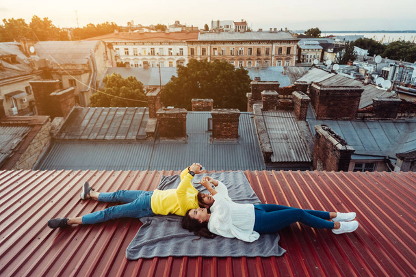 Ένας όμορφος άντρας και ένα νεαρό κορίτσι κείτονται στην οροφή και κρατούν τους εξυπνάκηδες.. - Φωτογραφία, εικόνα