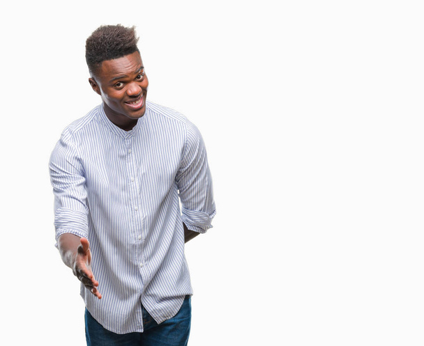 Fiatal afroamerikai férfi mosolyogva barátságos kínál kézfogás, mint üdvözlés és barátságos elszigetelt háttérhez képest. Sikeres üzleti. - Fotó, kép