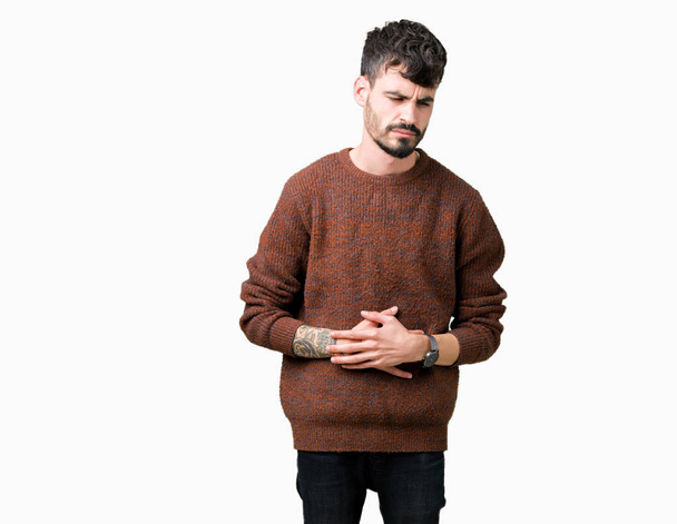 Young handsome man wearing winter sweater over isolated background with hand on stomach because nausea, painful disease feeling unwell. Ache concept. - Foto, imagen
