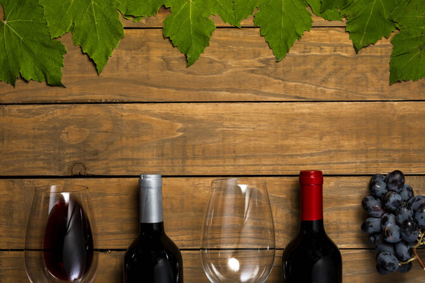Verres de bouteilles de vin et de raisins et feuilles sur fond de bois. Vue supérieure avec espace de copie
. - Photo, image