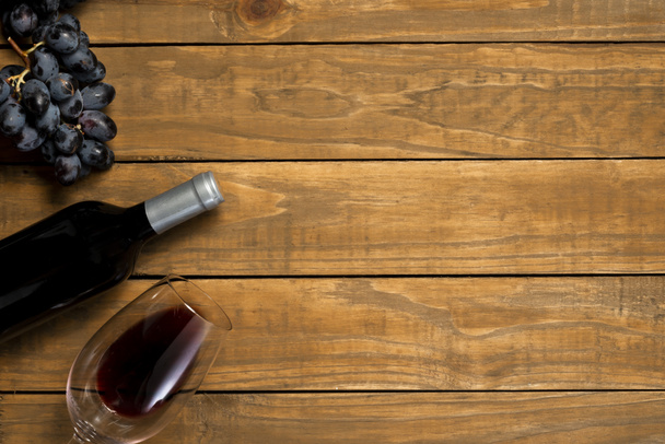 Bottle of wine glass and grapes on wooden background. Top view with copy space. - Photo, Image