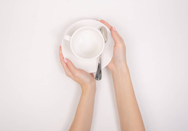 White saucer cup spoon in hand - Фото, изображение