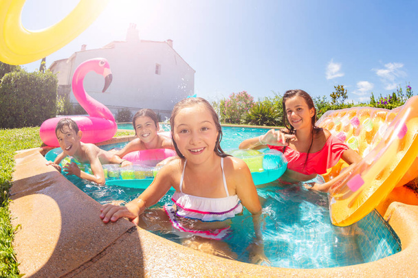 Портрет девочки-подростка, отдыхающей с друзьями в открытом бассейне во время летних каникул, улыбающейся и смотрящей в камеру
 - Фото, изображение