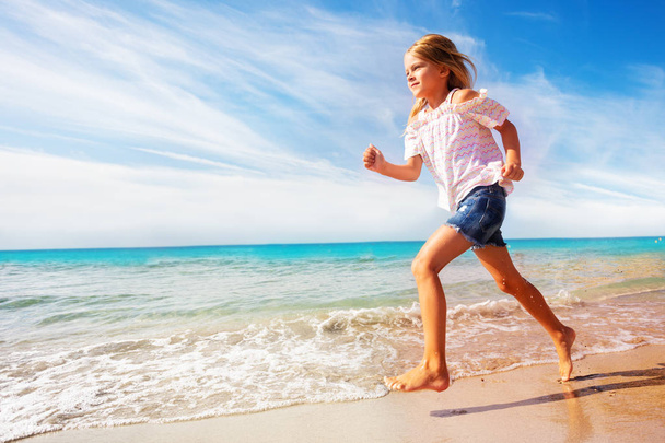 Side view portrait of beautiful girl running along sandy beach in summer - Фото, зображення
