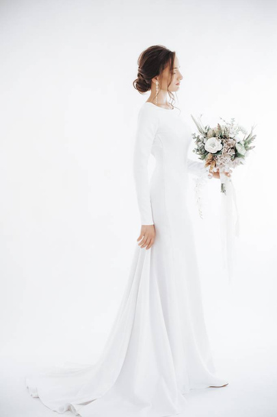 Bela noiva jovem em vestido de noiva branco posando com flores
 - Foto, Imagem