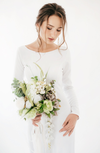 Beautiful young bride in white wedding dress posing with flowers - Fotoğraf, Görsel