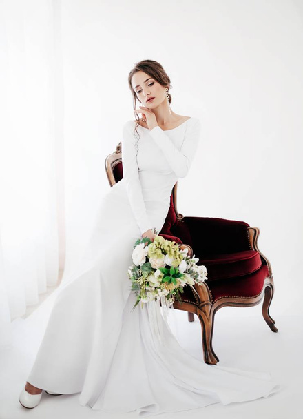 Belle jeune mariée en robe de mariée blanche posant avec des fleurs
 - Photo, image