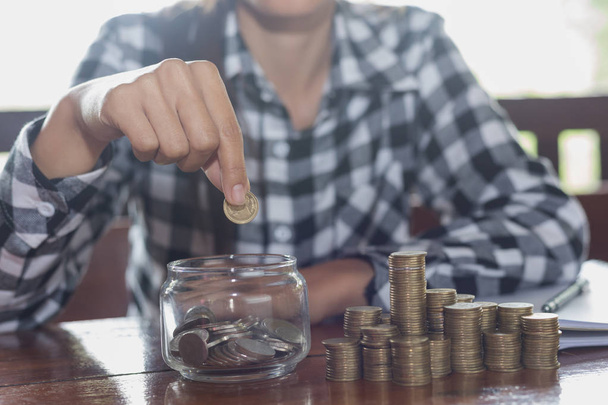 La mano de la mujer poniendo moneda en un vaso de botella para ahorrar dinero, ahorrando concepto de dinero
 - Foto, Imagen