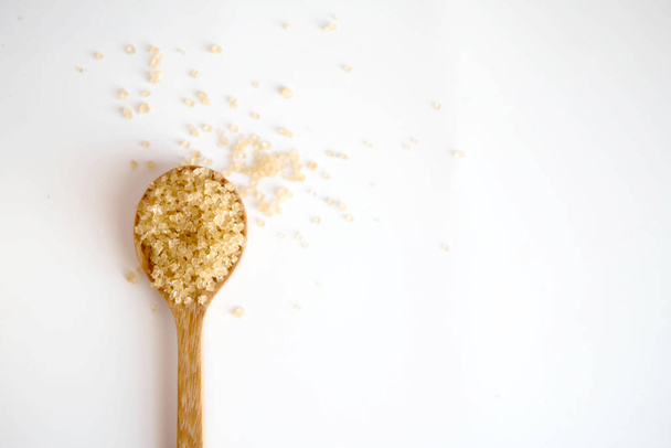 Brown sugar in a wooden spoon on white background with copy space. - Фото, зображення